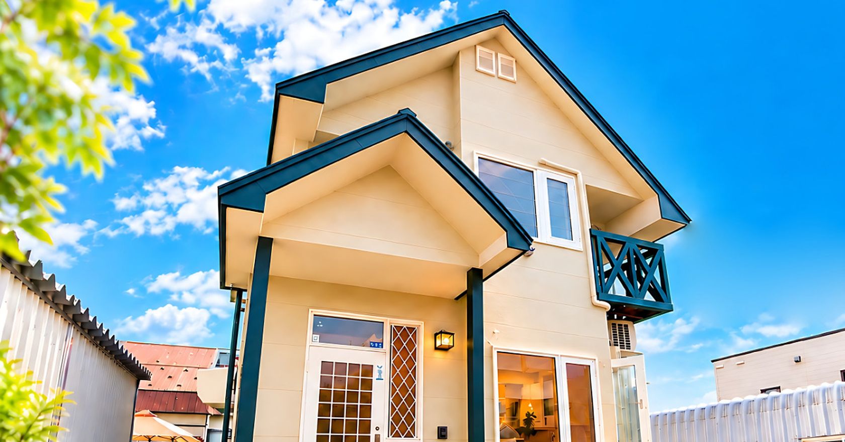 Mame & Hana Sunny West, a cream two-storey house with blue trim under a summer sky