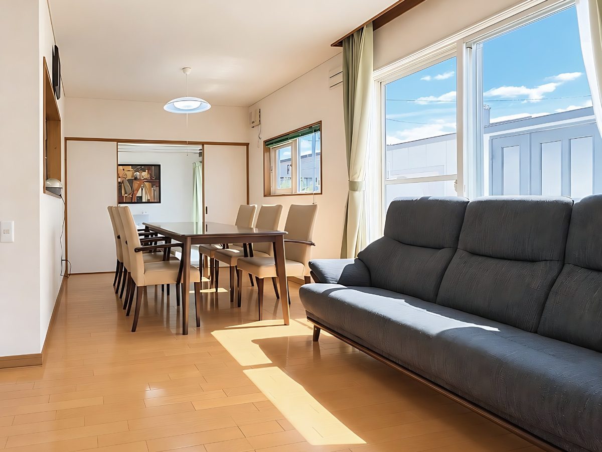 Sunny living room with a grey sofa and the dining table beyond